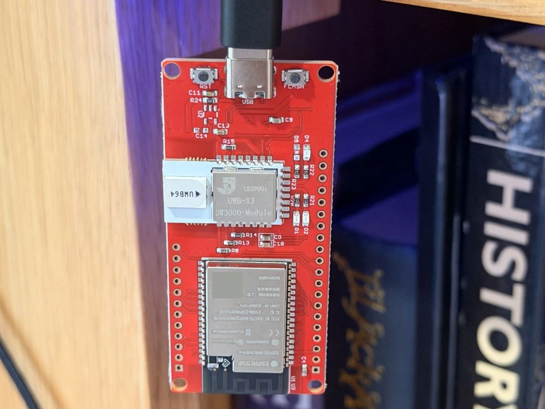 A red Makerfabs ESP32-WROVER development board with USB connected and its UWB module and antenna visible.